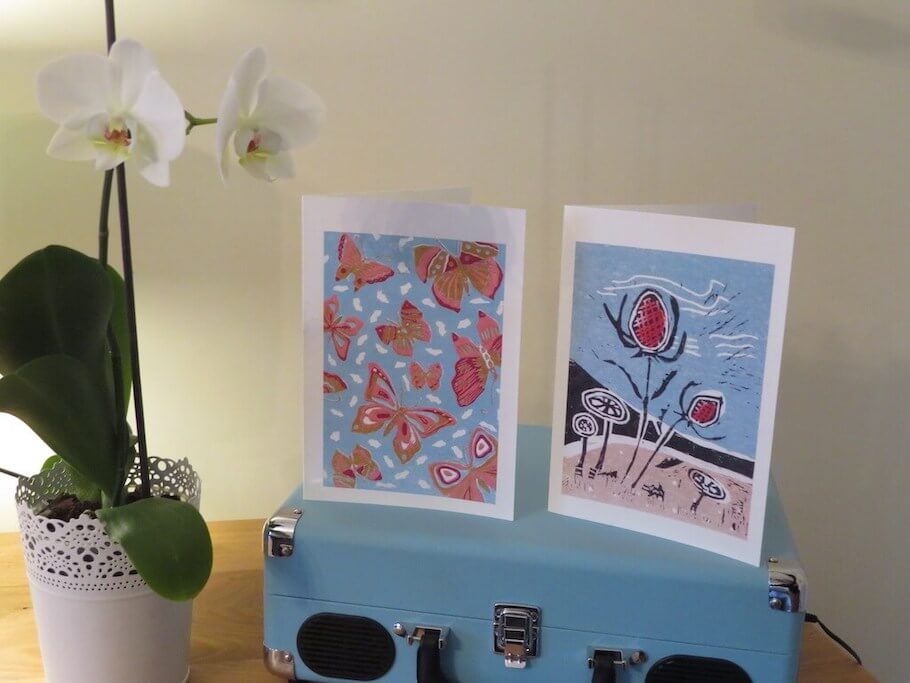 Two lino print greetings cards titled 'Beach Seedhead' and 'Butterfly Skies'.